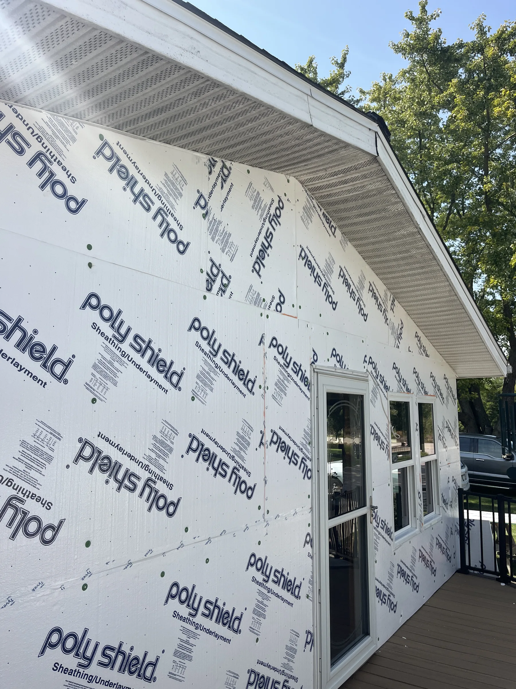 Poly Shield sheathing/underlayment panels installed on a house exterior wall beside a patio door and windows